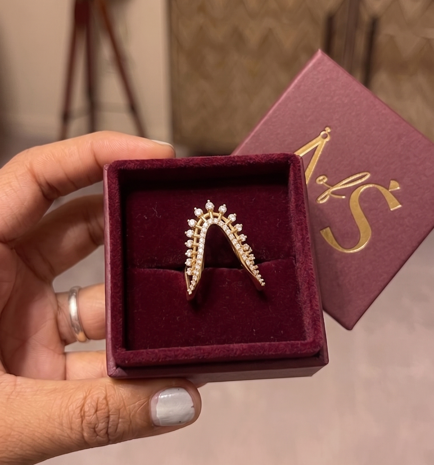 A silver-toned ring featuring a sweeping, open triangular design